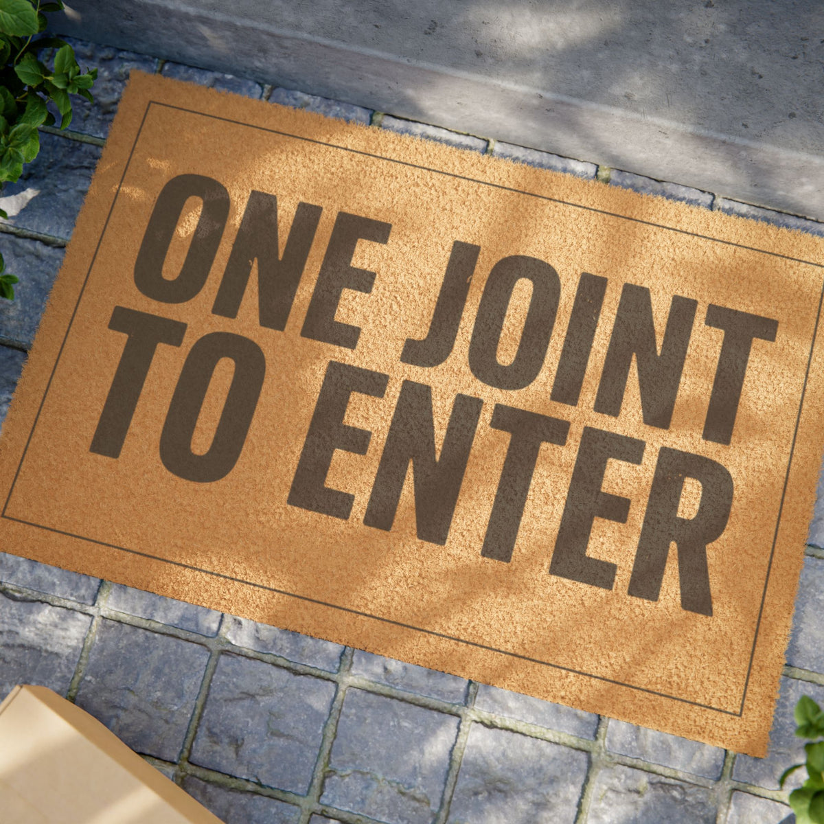 Close view of the One Joint to Enter coir doormat on a stone patio in dappled sunlight