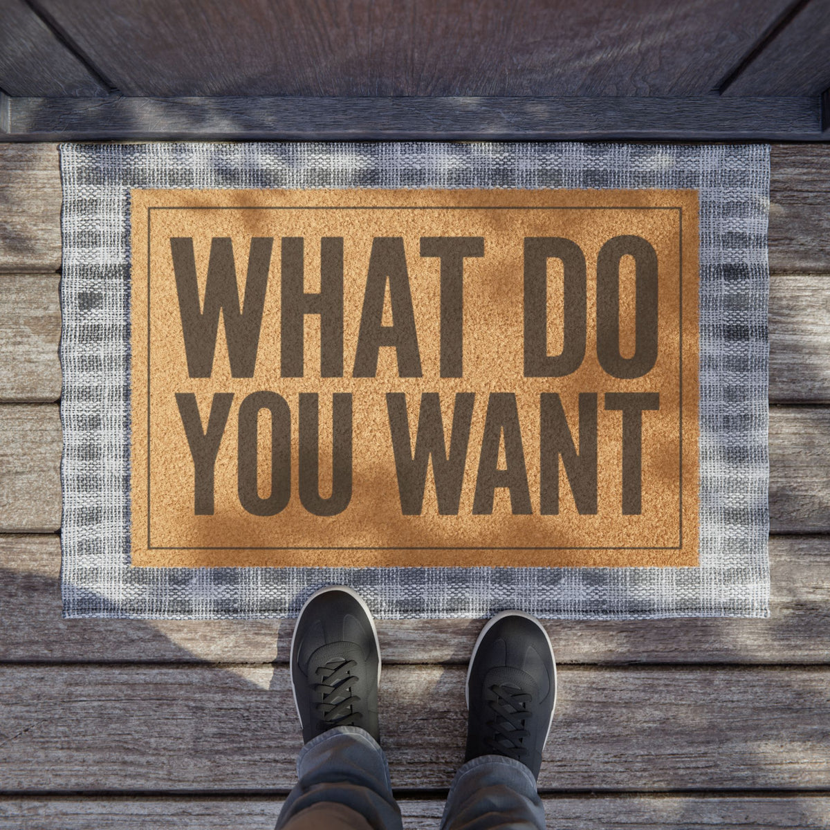 What Do You Want coir doormat on a wooden porch seen from above with a pair of shoes at the edge