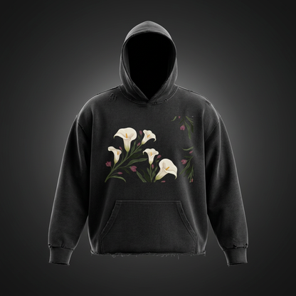 Black calla lily vintage wash raw edge hoodie on a dark studio backdrop with white lilies on the chest and a kangaroo pocket
