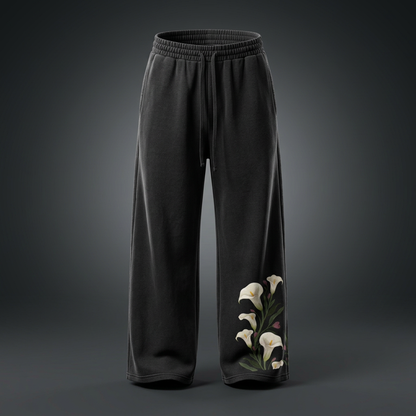 Black calla lily wide leg sweatpants on a dark studio backdrop with white lilies climbing the lower leg