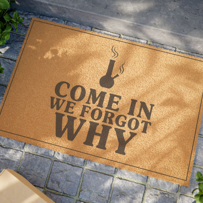 Close view of the Come In We Forgot Why Smoke Icon Layout coir doormat on a stone patio in dappled sunlight