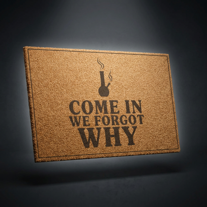 Come In We Forgot Why Smoke Icon Layout coir doormat with dark lettering on natural tan coir, shown on a dark studio backdrop