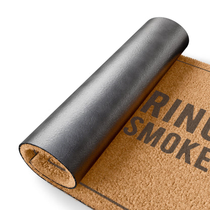 Rolled-up corner of the Did You Bring Anything to Smoke coir doormat showing the black vinyl backing