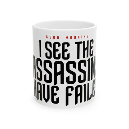 Funny coffee mug printed with "GOOD MORNING / I SEE THE ASSASSINS HAVE FAILED", front view