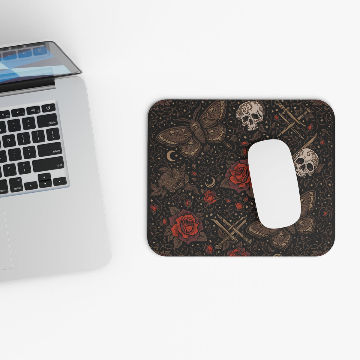 Top view of the skull moth mouse pad beside a laptop keyboard