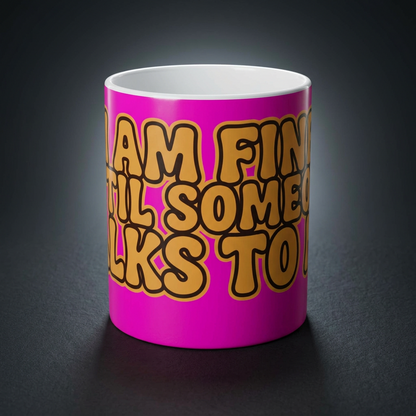 Funny coffee mug printed with "I AM FINE UNTIL SOMEONE TALKS TO ME", shown on a dark studio background