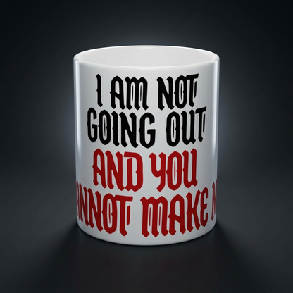 Funny coffee mug printed with "I AM NOT GOING OUT AND YOU CANNOT MAKE ME", shown on a dark studio background