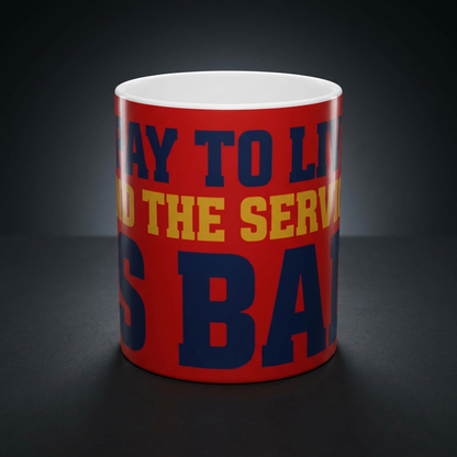 Funny coffee mug printed with "I PAY TO LIVE AND THE SERVICE IS BAD", shown on a dark studio background