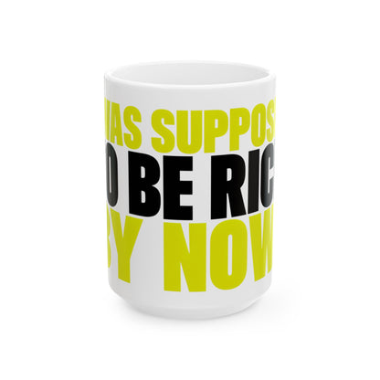Funny coffee mug printed with "I WAS SUPPOSED TO BE RICH BY NOW", three-quarter view with the handle on the right