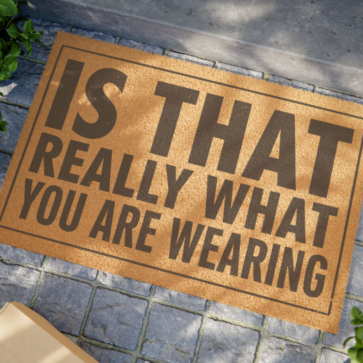 Close view of the Is That Really What You Are Wearing coir doormat on a stone patio in dappled sunlight