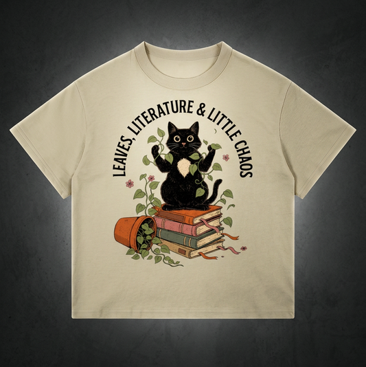 Kids’ loose-fit drop-shoulder tee with a black cat on books beside a tipped plant pot, Leaves, Literature & Little Chaos front print