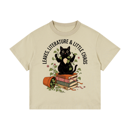 Kids’ loose-fit drop-shoulder tee with a black cat on books beside a tipped plant pot, Leaves, Literature & Little Chaos front print