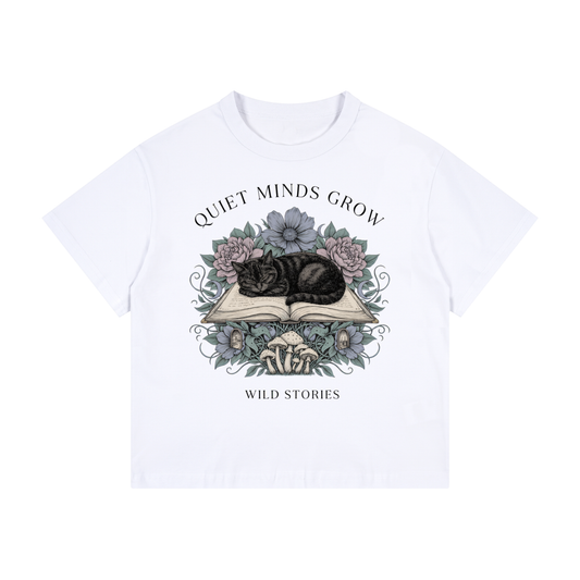 Kids’ loose-fit drop-shoulder tee with a sleeping black cat on an open book among flowers, Quiet Minds Grow, Wild Stories front print