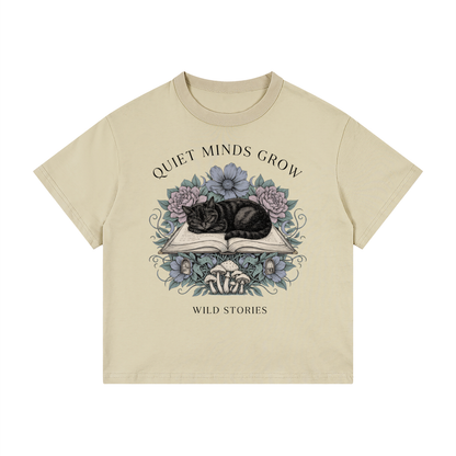 Kids’ loose-fit drop-shoulder tee with a sleeping black cat on an open book among flowers, Quiet Minds Grow, Wild Stories front print