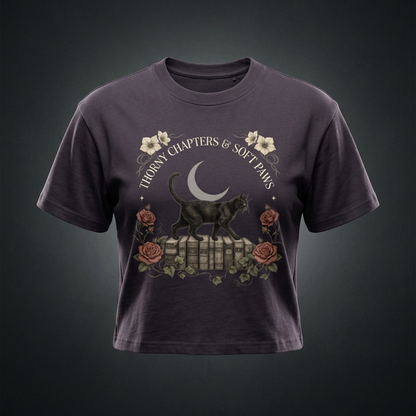 Kids’ loose-fit drop-shoulder tee with a black cat walking over old books under a crescent moon, Thorny Chapters & Soft Paws front print