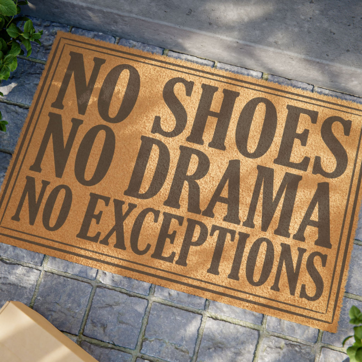 Close view of the No Shoes No Drama No Exceptions coir doormat on a stone patio in dappled sunlight