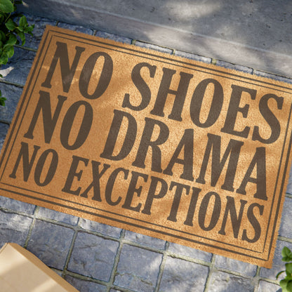 Close view of the No Shoes No Drama No Exceptions coir doormat on a stone patio in dappled sunlight