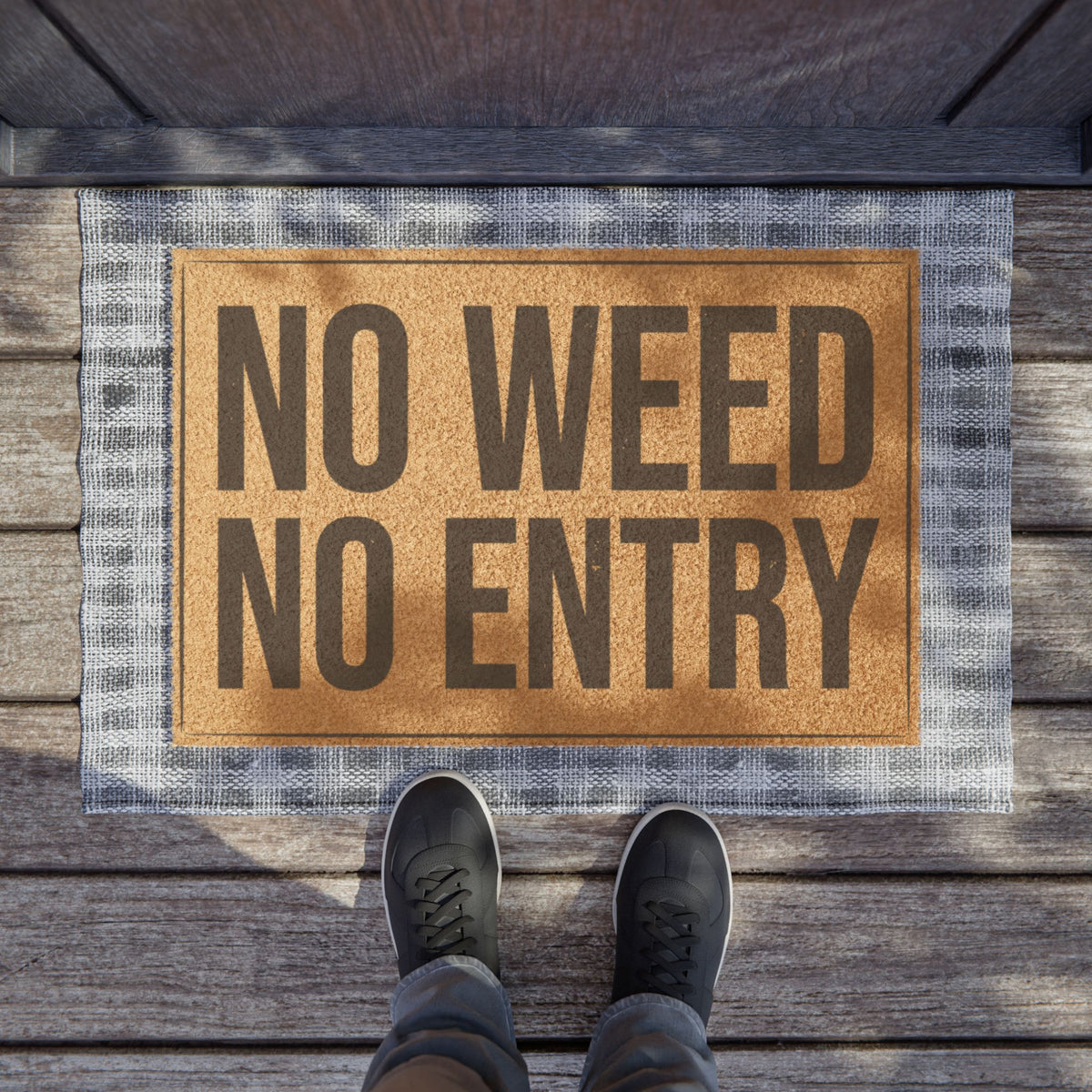 No Weed No Entry coir doormat on a wooden porch seen from above with a pair of shoes at the edge