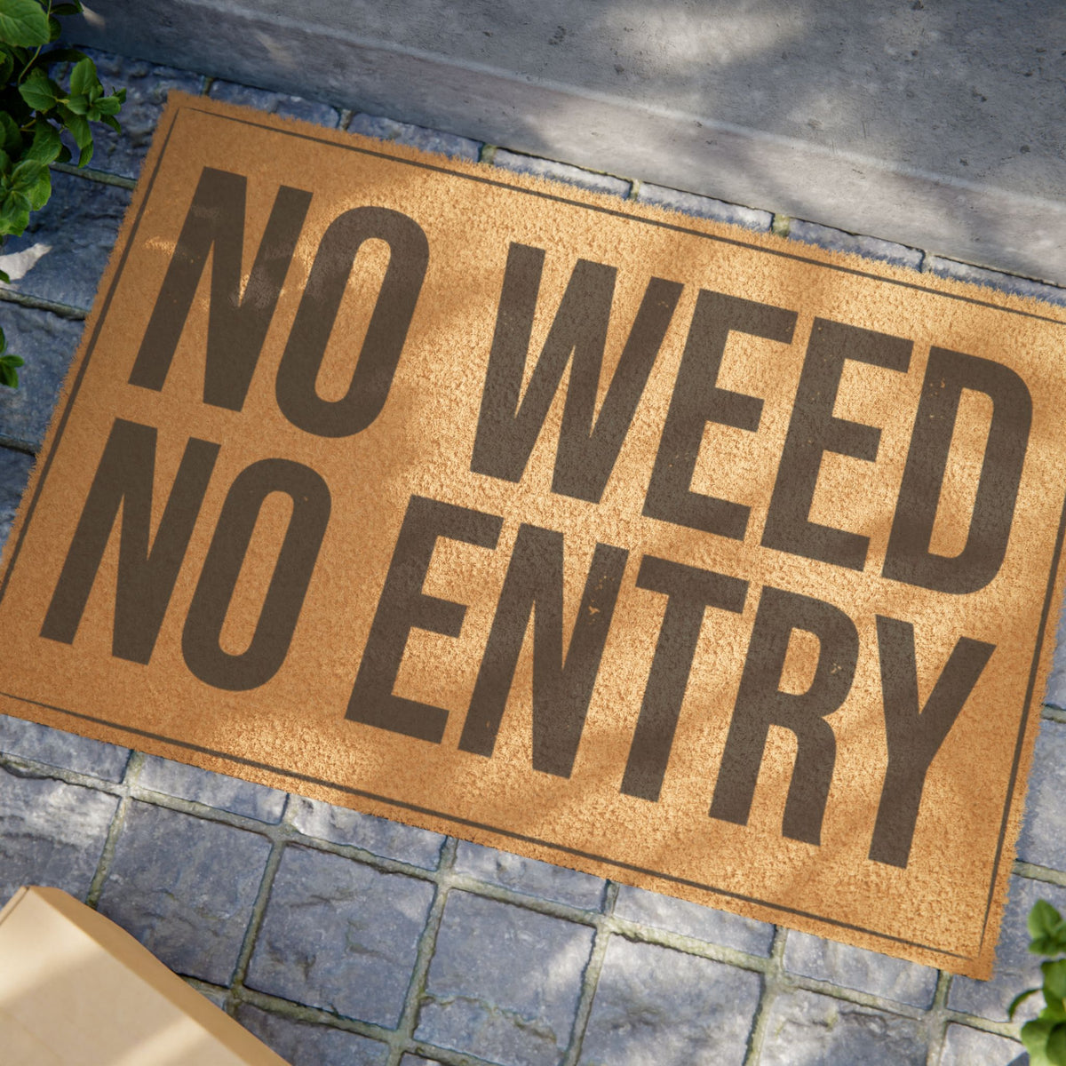 Close view of the No Weed No Entry coir doormat on a stone patio in dappled sunlight