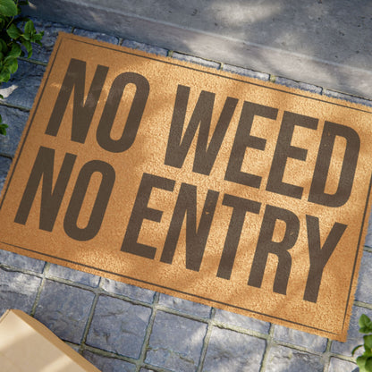 Close view of the No Weed No Entry coir doormat on a stone patio in dappled sunlight