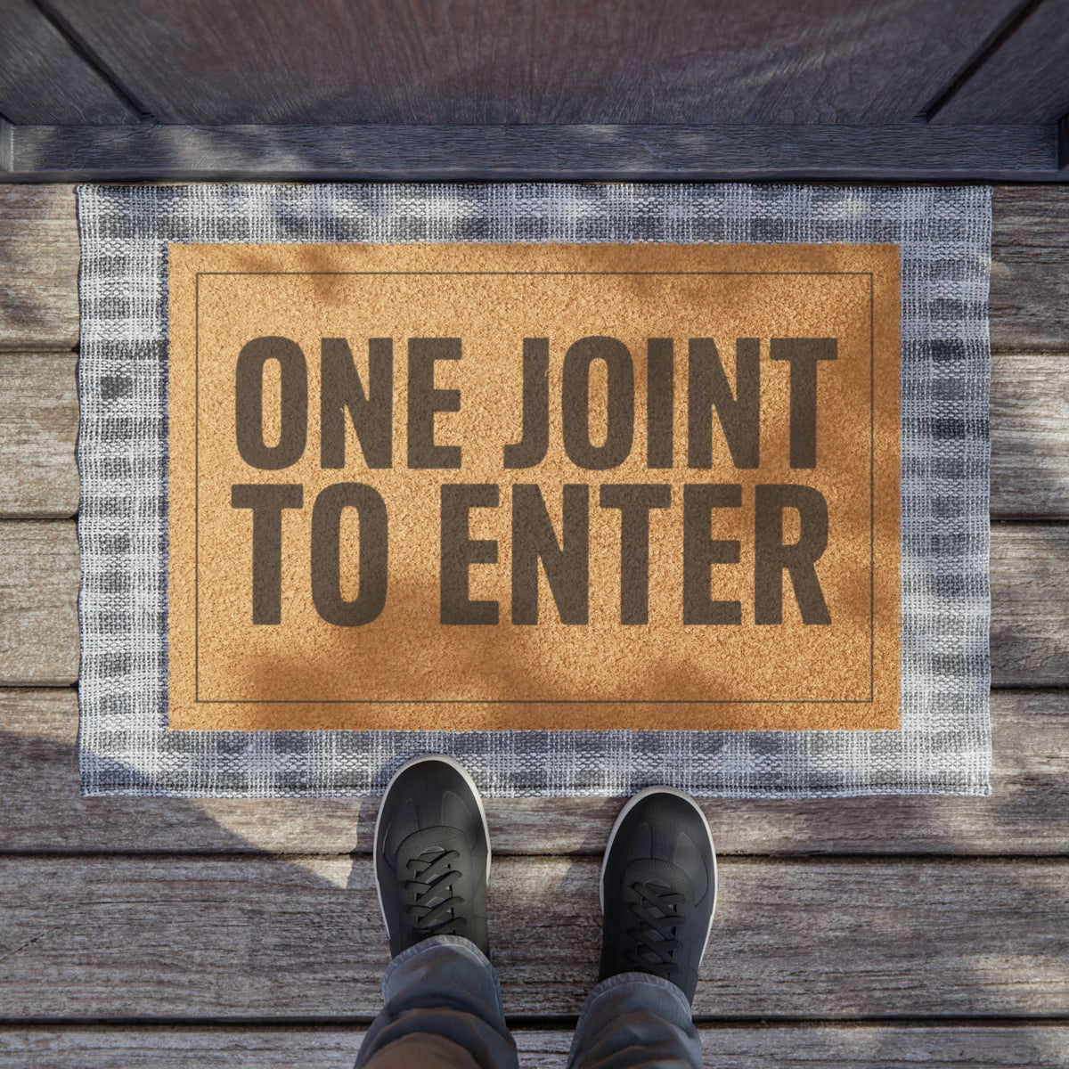 One Joint to Enter coir doormat on a wooden porch seen from above with a pair of shoes at the edge
