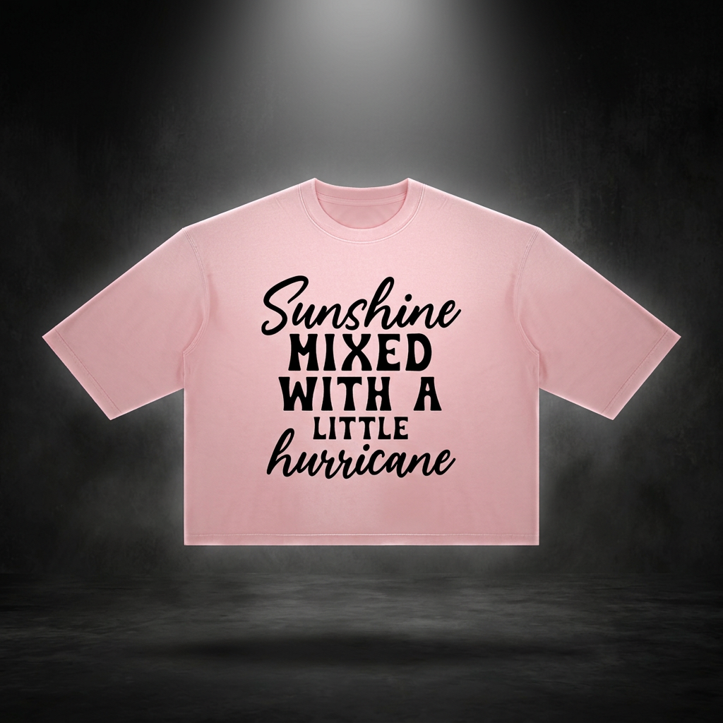 Pink boxy vintage wash t-shirt with black Sunshine mixed with a little hurricane lettering floating on a dark studio backdrop