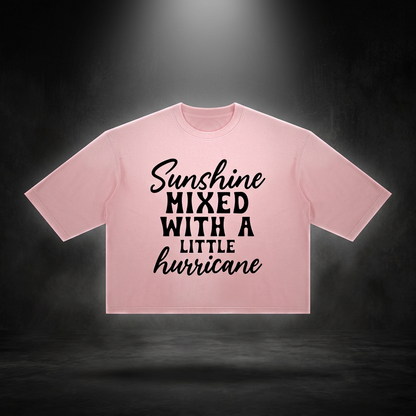 Pink boxy vintage wash t-shirt with black Sunshine mixed with a little hurricane lettering floating on a dark studio backdrop