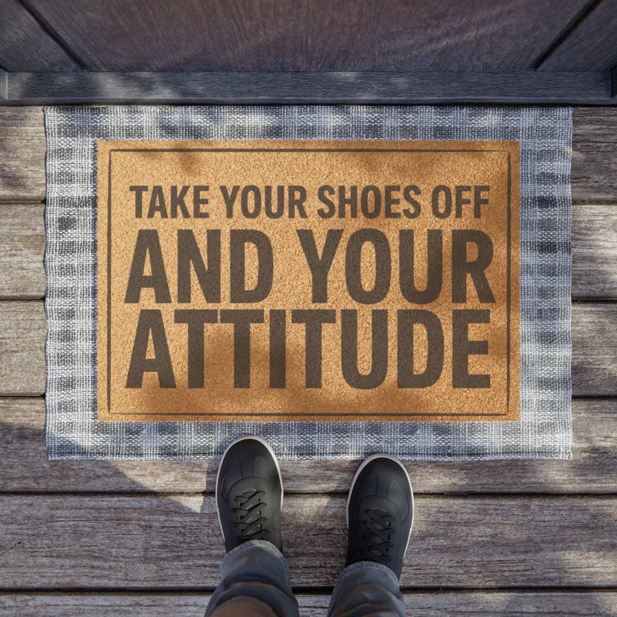 Take Your Shoes Off and Your Attitude Stacked Layout coir doormat on a wooden porch seen from above with a pair of shoes at the edge