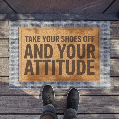 Take Your Shoes Off and Your Attitude Stacked Layout coir doormat on a wooden porch seen from above with a pair of shoes at the edge