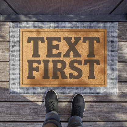 Text First coir doormat on a wooden porch seen from above with a pair of shoes at the edge