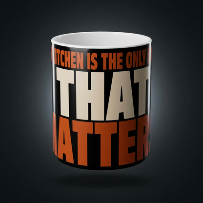Funny coffee mug printed with "THE KITCHEN IS THE ONLY ROOM THAT MATTERS", shown on a dark studio background