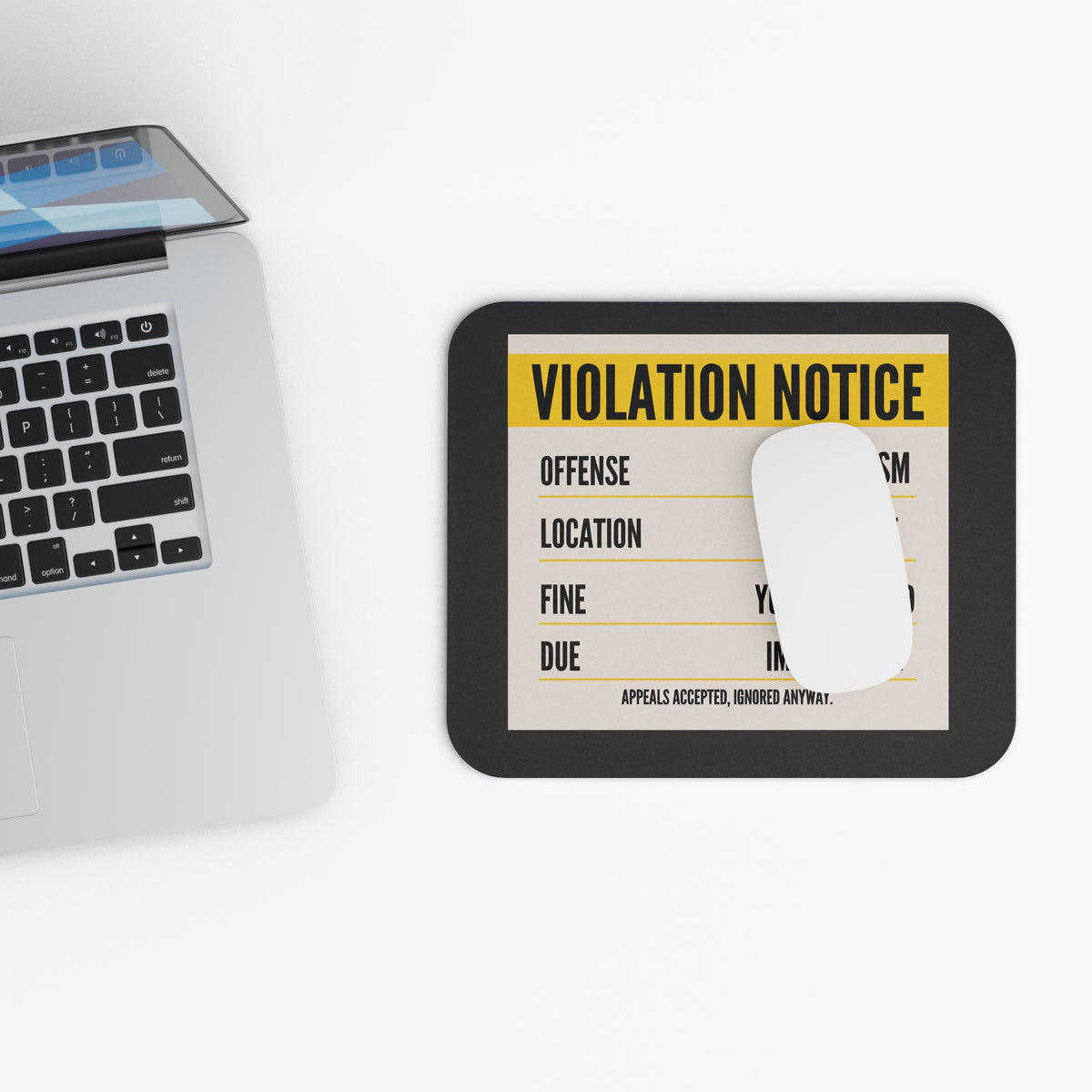 Top view of the violation notice mouse pad beside a laptop keyboard