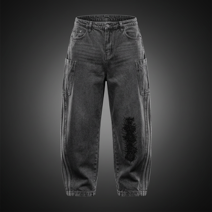 Black vintage wash barrel leg jeans with black Gothic FAFO lettering on the knee and light stripes down the side seams, shown against a dark studio backdrop