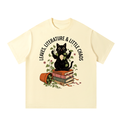 Unisex oversized heavyweight cotton tee with a black cat on books beside a tipped plant pot, Leaves, Literature & Little Chaos front print