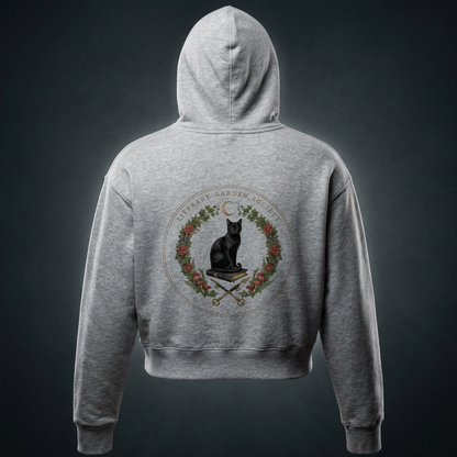 Women’s Literary Garden Society Cropped Drop-Shoulder Hoodie in gray, back view with the black cat and roses crest, on a dark studio background