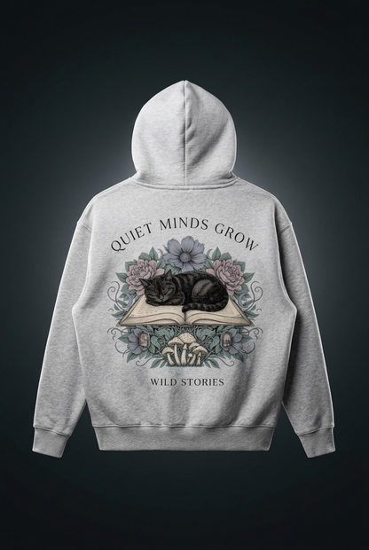 Unisex oversized boxy fleece hoodie with a sleeping black cat on an open book among flowers, Quiet Minds Grow, Wild Stories back print