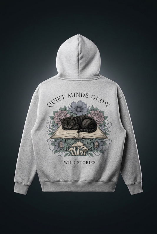 Unisex oversized boxy fleece hoodie with a sleeping black cat on an open book among flowers, Quiet Minds Grow, Wild Stories back print