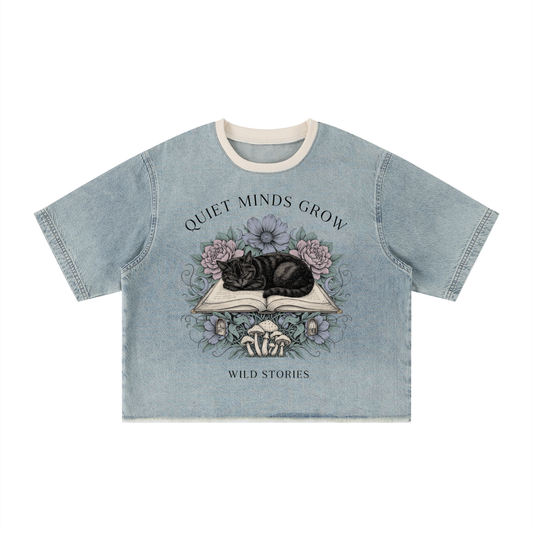 Unisex vintage-wash boxy tee with a raw hem with a sleeping black cat on an open book among flowers, Quiet Minds Grow, Wild Stories front print
