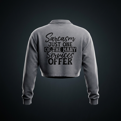 Cement gray women's vintage wash cropped collared sweatshirt with black cursive and bold capital Sarcasm just one of the many services offer lettering with a black band on the back shown against a dark studio backdrop
