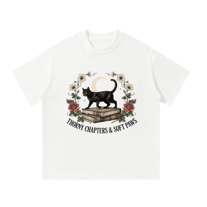 Unisex oversized heavyweight cotton tee with a black cat walking over old books under a crescent moon, Thorny Chapters & Soft Paws front print