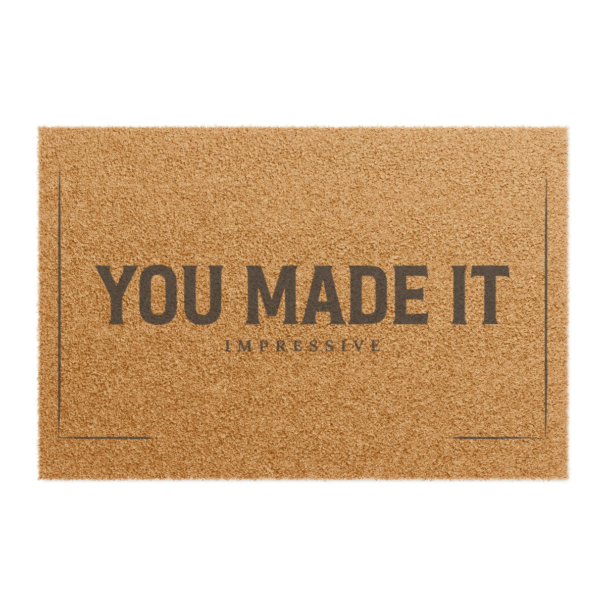 Top view of the You Made It Impressive coir doormat, dark lettering inside a thin border on natural tan fiber