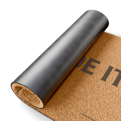 Rolled-up corner of the You Made It Impressive coir doormat showing the black vinyl backing